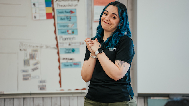 Nicole with her hands clasped in a classroom. 